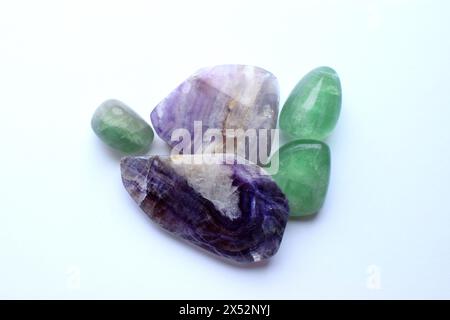 Des sections de belles pierres de fluorite violette rayées et de fluorite verte se rapprochent sur un fond blanc. Cristaux de Chakra de guérison Banque D'Images