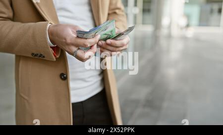 Homme hispanique comptant le ringgit malaisien dans un cadre urbain en plein air, dépeignant la vie urbaine et la finance. Banque D'Images