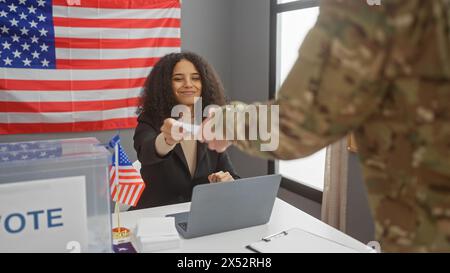 Dans un centre électoral américain, une femme accepte un bulletin de vote d'un soldat sous le drapeau américain. Banque D'Images