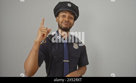 Un policier afro-américain confiant pointe vers le haut, isolé sur fond blanc, incarnant autorité et orientation. Banque D'Images