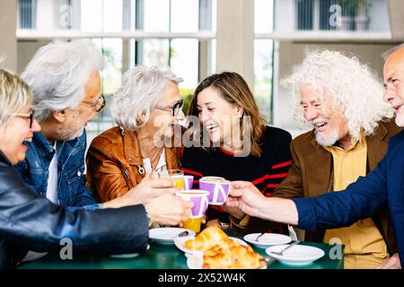 Heureux groupe de personnes âgées riant et appréciant le café au bar cafétéria Banque D'Images