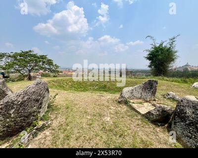 Phonsavan, Laos. 13 avril 2024. Les vaisseaux de pierre endommagés se trouvent dans les jarres de la plaine d'argile, site 1, devant un énorme cratère de bombe. Les États-Unis bombardent massivement le Laos entre 1964 et 1973. Seuls les sites 1, 2 et 3 sont accessibles aux visiteurs en raison du grand nombre de bombes non explosées. La « plaine des jarres » est considérée comme une sorte de Stonehenge d'Asie du Sud-est et l'un des sites archéologiques les plus énigmatiques au monde. Certains des pots en pierre ont plus de 2000 ans. Crédit : Carola Frentzen/dpa/Alamy Live News Banque D'Images