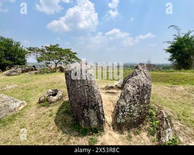 Phonsavan, Laos. 13 avril 2024. Les vaisseaux de pierre endommagés se trouvent dans les jarres de la plaine d'argile, site 1, devant un énorme cratère de bombe. Les États-Unis bombardent massivement le Laos entre 1964 et 1973. Seuls les sites 1, 2 et 3 sont accessibles aux visiteurs en raison du grand nombre de bombes non explosées. La « plaine des jarres » est considérée comme une sorte de Stonehenge d'Asie du Sud-est et l'un des sites archéologiques les plus énigmatiques au monde. Certains des pots en pierre ont plus de 2000 ans. Crédit : Carola Frentzen/dpa/Alamy Live News Banque D'Images