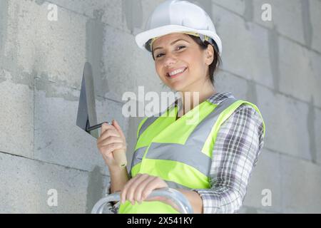 heureuse ouvrière met du plâtre sur une spatule Banque D'Images