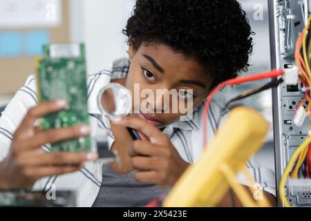 femme sérieuse travaillant avec le circuit imprimé avec la loupe Banque D'Images