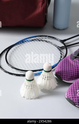 Volants de badminton en plume, raquettes et baskets sur fond gris Banque D'Images