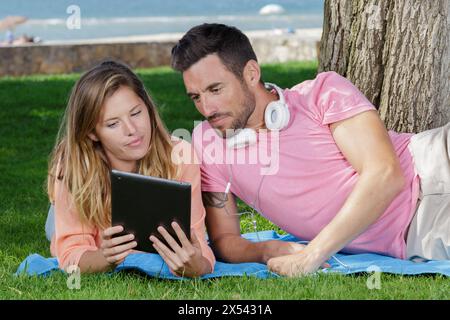 un homme et une femme avec une tablette gisaient sur l'herbe Banque D'Images