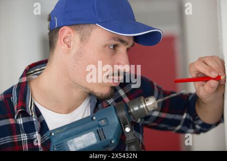 workman marquage d'un point avec un crayon pour percer un trou Banque D'Images