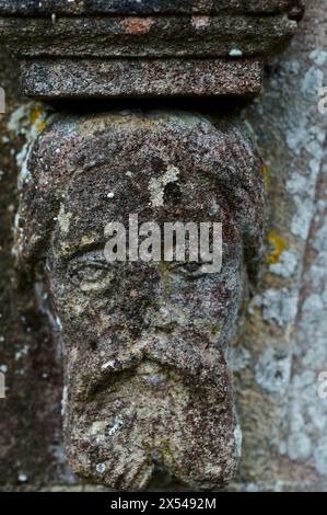 Gros plan d'une tête de corbeau en pierre altérée à la base d'une arche de porte d'église, Herstmonceux, East Sussex Banque D'Images