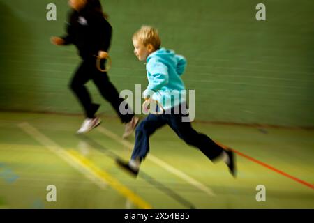 Élèves de l'école primaire prenant part à une leçon d'EP avec mouvement flou. Banque D'Images