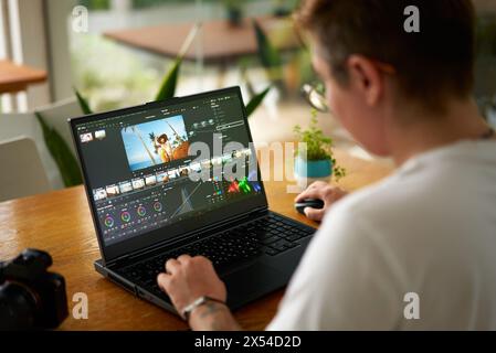 Coloriste vidéo professionnel ajuste les couleurs des séquences sur ordinateur portable dans un bureau lumineux. L'éditeur de l'industrie créative travaille sur l'étalonnage des films, améliore l'attrait visuel Banque D'Images