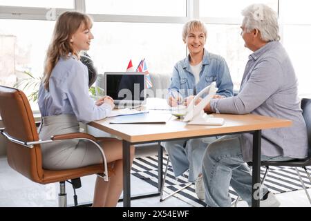 Couple mature avec agent de voyage remplissant la demande de visa au bureau Banque D'Images