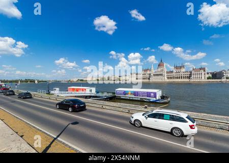 Voitures conduisant sur rakpart (route le long du Danube) avec bâtiment du Parlement hongrois, Budapest, Hongrie Banque D'Images
