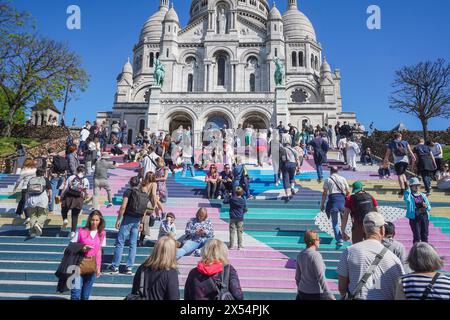 Paris, France. 7 mai 2024. Touristes appréciant le soleil chaud du printemps sur les marches peintes pour les jeux olympiques de la Basilique du Sacré-Cœur de Montmartre à Paris. Credit : amer Ghazzal/Alamy Live News Banque D'Images