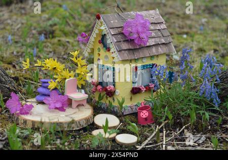 Mignonne maison de poupée fée avec des fleurs de printemps à l'extérieur dans le jardin. Belle miniature pour cartes de voeux, mariage ou concept d'anniversaire, immobilier, downsi Banque D'Images