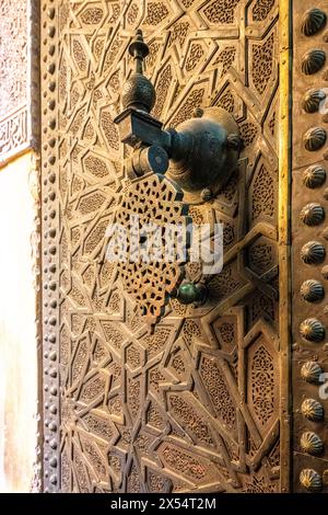 Un frappeur de porte en bronze détaillé orne l'entrée de la Madrasa Cherratine dans la médina de Fès. Banque D'Images