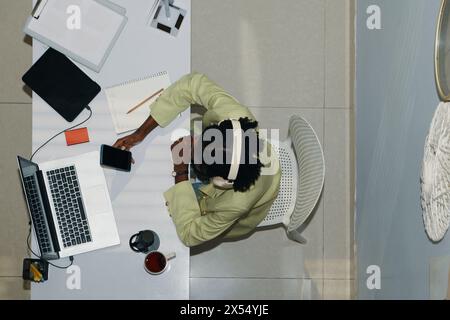 Femme d'affaires noire portant des écouteurs lorsqu'elle travaille au bureau Banque D'Images