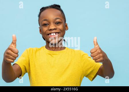 Mignon garçon à la peau foncée regardant excité et souriant gentiment Banque D'Images