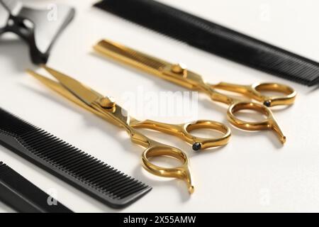 Outils de coiffure. Différents ciseaux et peignes sur table blanche, gros plan Banque D'Images