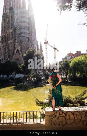 Eine Frau posiert mit einem Strauß roter Rosen auf einem Mäuerchen vor der Sagrada Familia in Barcelona, Spanien Barcelona Katalonien Spanien *** A WO Banque D'Images