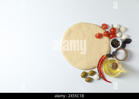Pâte à pizza fraîche et produits isolés sur blanc, vue de dessus Banque D'Images