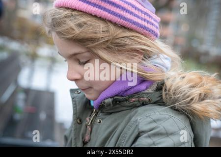 Jeune jolie fille aux longs cheveux blonds. Après l'école, pendant ses temps libres, elle aime jouer dans l'air frais et sain sur une aire de jeux avec les enfants. Banque D'Images