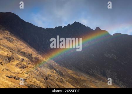 Arc-en-ciel dans le col de Glencoe en dessous de la crête d'Aonach Eagach dans les Highlands écossais, en Écosse. Printemps (mars) 2024. Banque D'Images