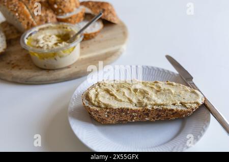 Morceau de pain avec houmous sur une assiette blanche Banque D'Images