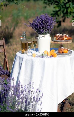 limonade, croissants, abricots et bouquet de lavande sur une table dans le jardin Banque D'Images
