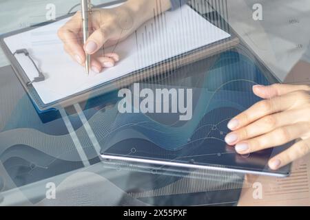 Gros plan de la femme avec de belles mains dans la tenue d'affaires, travaillant sur la tablette dans le bureau, prenant des notes. Graphiques de trading sur le foreg Banque D'Images