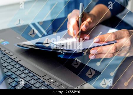 Gros plan de la femme avec de belles mains dans la tenue d'affaires, travaillant sur l'ordinateur portable dans le bureau, prenant des notes. Liste des tâches avec case cochée Banque D'Images