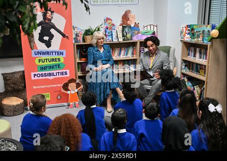 La reine Camilla et les élèves écoutent Joseph Coelho, lauréat des enfants de Waterstones et poète, lire un poème dans la bibliothèque de l'école primaire de Moreland à Londres, lors d'une visite pour ouvrir leur nouvelle bibliothèque du couronnement, la 50e d'une série de bibliothèques d'écoles primaires spéciales qui ont été transformées au cours des douze derniers mois avec l'aide du National Literacy Trust, pour marquer le couronnement. Date de la photo : mardi 7 mai 2024. Banque D'Images