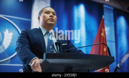 Portrait d'un représentant de l'organisation chinoise prenant la parole lors d'une conférence de presse. Ministre prononçant un discours au Congrès. Toile de fond avec les drapeaux des États-Unis d'Amérique et de la République populaire de Chine. Banque D'Images