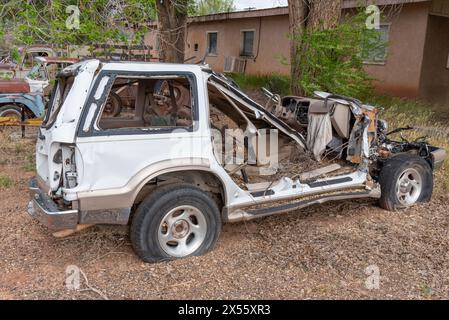 Voiture blanche endommagée par un accident stationnée sur un sol recouvert de feuilles, Arizona, USA. Banque D'Images