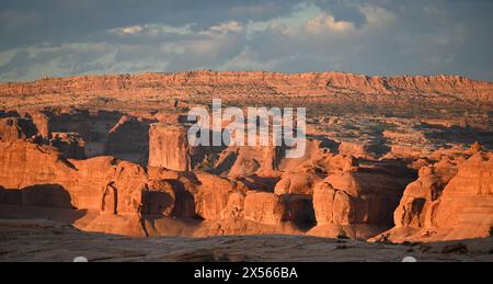 Un magnifique paysage panoramique de formations rocheuses rouges dans le parc national des Arches lors d'un coucher de soleil orageux. Banque D'Images