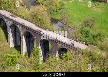 Les gens appréciant le soleil printanier marchent et font du vélo sur le sentier Monsal Trail au-dessus du viaduc Headstone à Monsal Head où il traverse la rivière Wye Banque D'Images