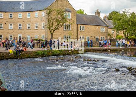 Les gens et les familles apprécient le soleil printanier et le temps ensoleillé sur les rives de la rivière Wye dans la ville de Derbyshire Peak District de Bakewell Banque D'Images