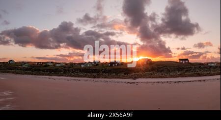 Cabanes de plage éloignées avec vue sur la mer sur les dunes de sable de Northumbrian surplombant la plage d'Embleton Bay au coucher du soleil Banque D'Images