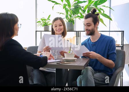 Gestionnaire de voyage de mariage, courtier immobilier, agent d'assurance bancaire travaillant avec un jeune couple Banque D'Images