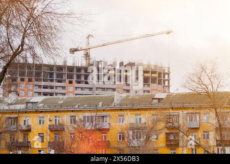 Maison en construction et grue de construction. Ancienne maison et nouvelle maison. Concept d'armement ménager... Banque D'Images