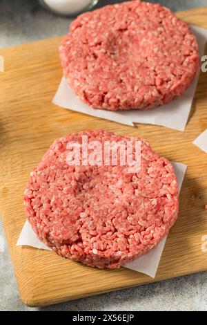 Des hamburgers de bœuf farcis à l'herbe crue prêts à cuire Banque D'Images