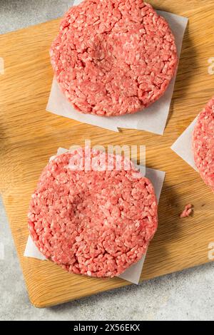 Des hamburgers de bœuf farcis à l'herbe crue prêts à cuire Banque D'Images