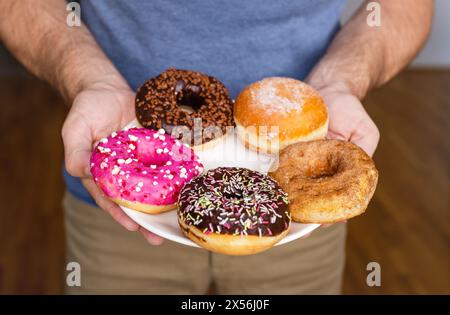 Divers types de beignets sur la plaque gros plan dans les mains de l'homme. Banque D'Images