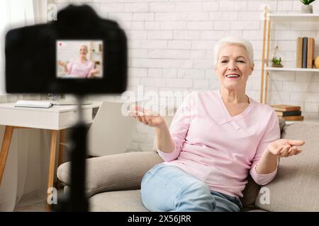 Friendly senior woman sitting on sofa vlogger datant en ligne Banque D'Images