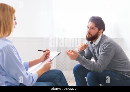 Beau jeune homme assis sur la table et de parler à un psychologue Banque D'Images