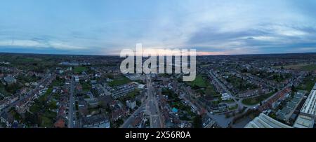 Bergensesteenweg, Sint-Pieters-Leeuw, Bruxelles, Belgique, 26 mars, 2024, cette prise de vue aérienne panoramique capture la beauté tranquille d'une banlieue au crépuscule, avec des rues résidentielles et des maisons s'étendant au loin sous un ciel qui s'estompe. L'image encapsule l'atmosphère sereine de la banlieue, renforcée par la douce lueur du coucher de soleil à l'horizon. Crépuscule au-dessus d'un paysage de banlieue : vue aérienne panoramique. Photo de haute qualité Banque D'Images