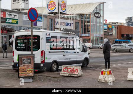 gothenburg, Suède - 22 janvier 2022 : une personne attend à l'extérieur d'une voiture de test covid fermée sur un parking. Obstacles concrets à la circulation au sol. Shopp Banque D'Images