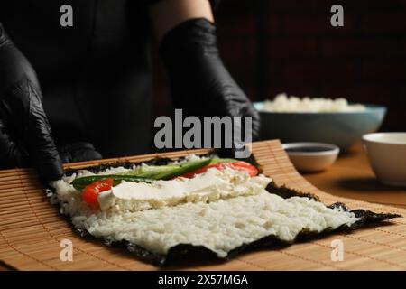 Chef en gants faisant rouler des sushis à table, gros plan Banque D'Images