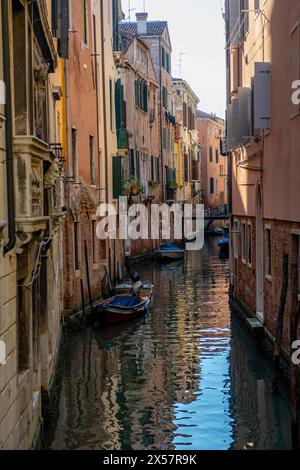 Canal étroit avec des bateaux, maisons reflétées dans l'eau, Venise, Vénétie, Italie Banque D'Images