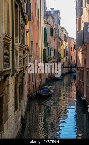 Canal étroit avec des bateaux, maisons reflétées dans l'eau, Venise, Vénétie, Italie Banque D'Images